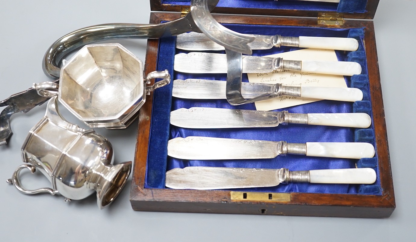 A George V silver octagonal cream jug and sugar bowl, Collingwood & Co, London, 1930, a cased set of six pairs of mother of pearl handled fish eaters and a silver plated claret jug handle.